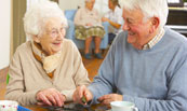 a cute senior couple playing dominoes